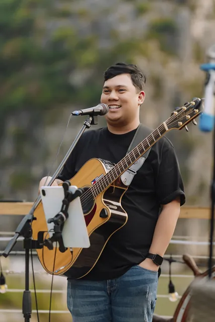 Ralph smiling with his guitar beside the bay